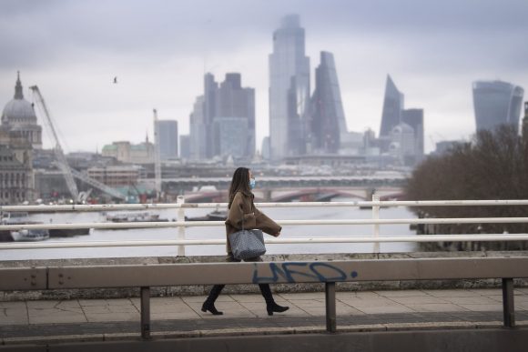 Woman wearing a facemask walks over an empty Waterloo Bridge, PA pic